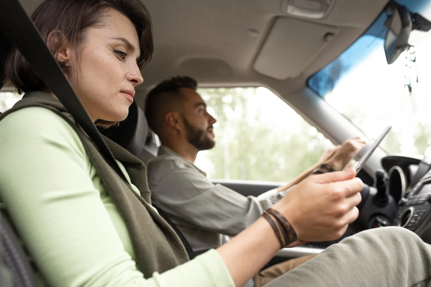 Una pasajera consulta una tablet junto al conductor dentro de un coche